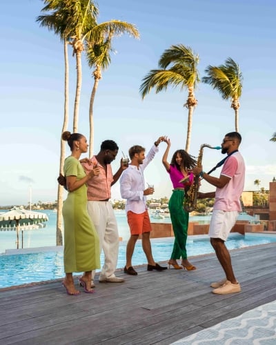 A group of friends are dancing with a saxophone player.