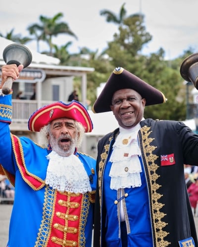 Bermudian tour guides in historical regalia welcome visitors.