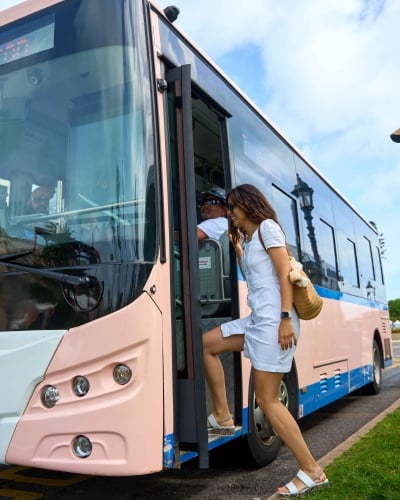 A man and a woman are hoping on an electric bus.
