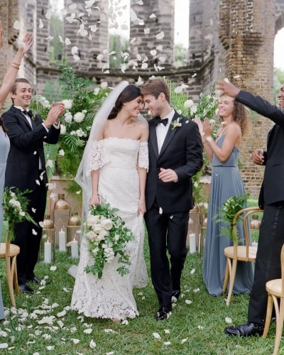 A couple is walking down the aisle with confetti.