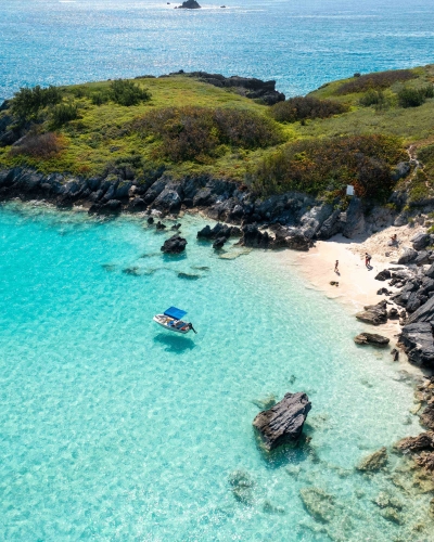 A family is on a beach with a boat anchored just a short ways off.