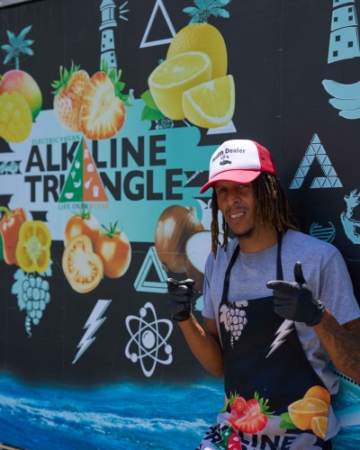 A man is posing outside of the vegan truck Alkaline Triangle