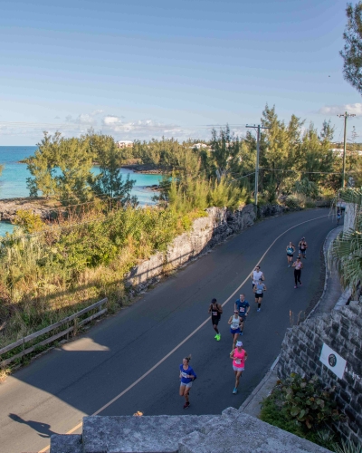 Aerial view of runners running in Bermuda with water on the side.
