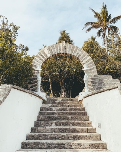 A stone archway and stairs leading up to palm trees on Bermuda