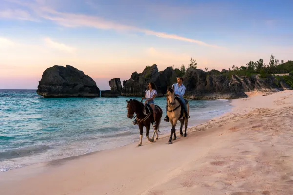 A couple riding horses on the beach
