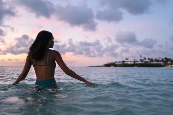 A woman in the ocean in Bermuda looking out at the sunset