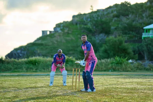 Two men playing cricket in Bermuda colours.