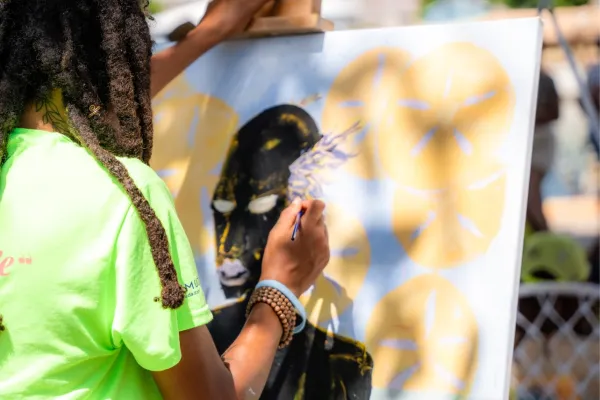 Artist Jahbarri Wilson works on a canvas in an outdoor space in Bermuda