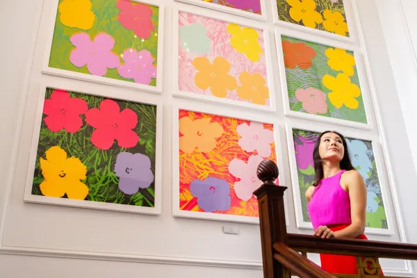 A woman poses in front of a full-wall piece of art near a balcony at a Bermudian gallery