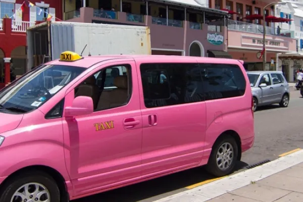 A pink taxi van parked on the street in Bermuda
