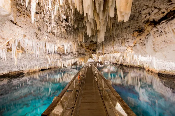 A walkway through the Crystal Cave in Bermuda, over blue-green waters and beneath hanging stalactites