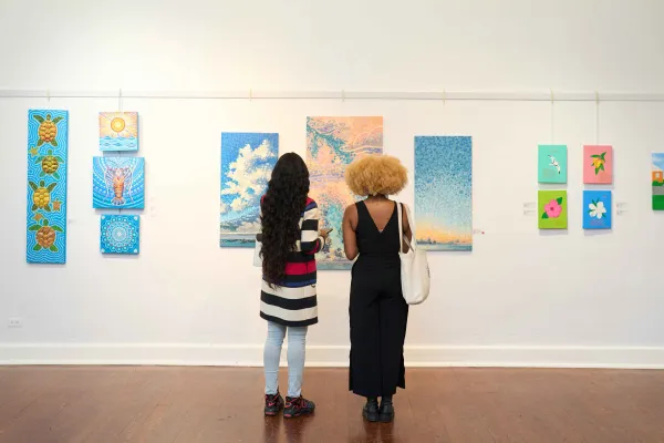 Two patrons looking at Bermudian art in a gallery