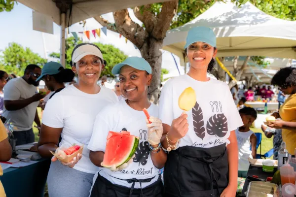 Three women posing with watermelon and other treats at Bermuda vegan fest