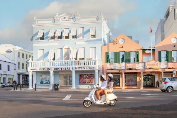 A couple on a motor scooter ride through a city centre in Bermuda