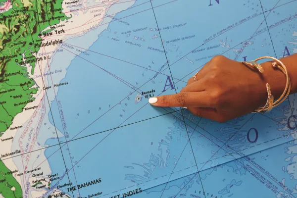A finger pointing at Bermuda's location on a map