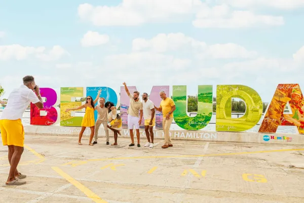 A group poses for a photo in from of a "Bermuda" sign