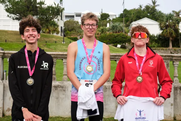 Three young athletes with medals around their necks, standing and smiling