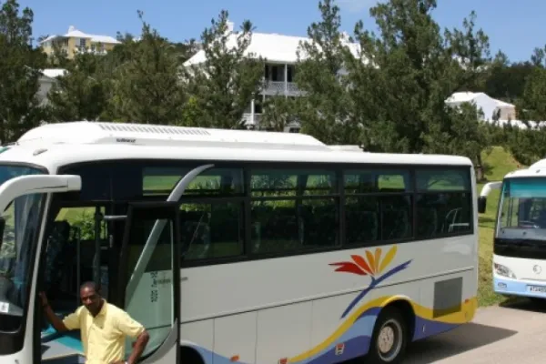 A man stands next to a large tour bus  in Bermuda
