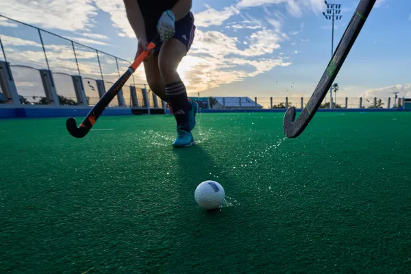 Two field hockey players swing their sticks at a ball in Bermuda