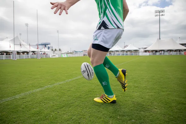 A person kicking a rugby ball on a pitch in Bermuda