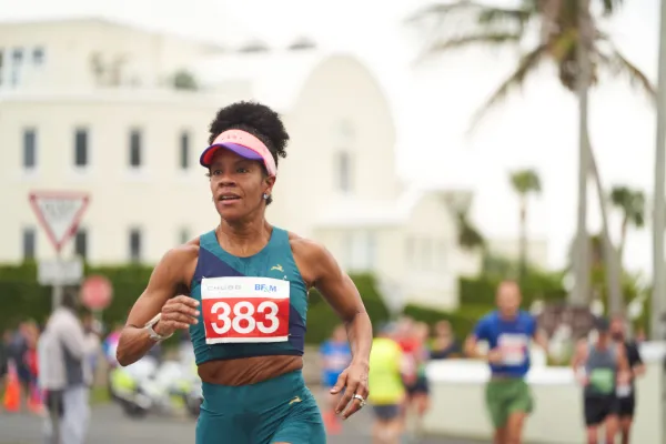 A woman running through a Bermudian city in the Chubb 10k race