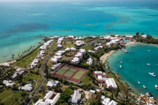 An aerial view of a stretch of Bermuda coastline, with a tennis complex next to a cove