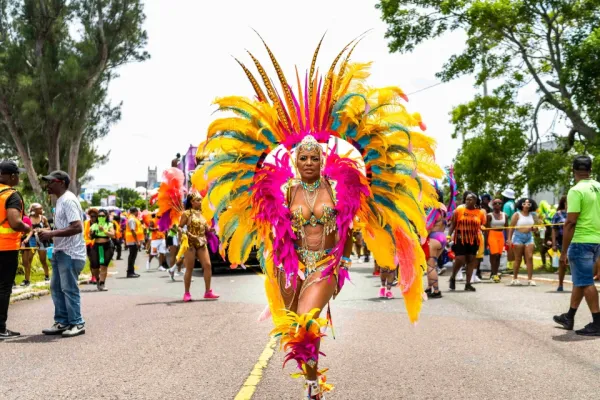 A woman in an elaborate colourful feathery outfit poses on the street during carnival in Bermuda