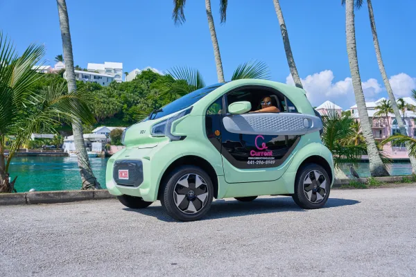 An electric microcar driving along the Bermudan harbour