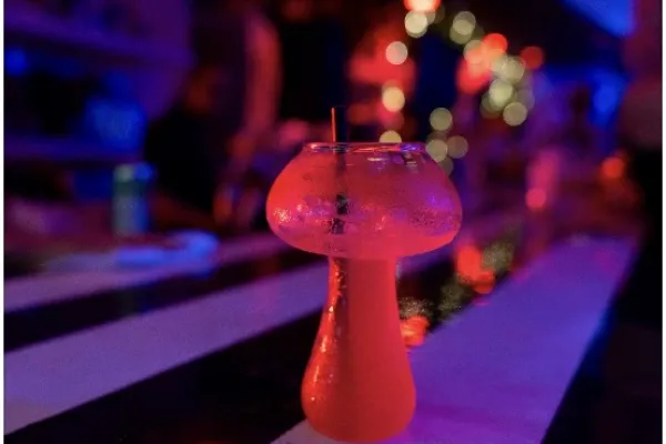 A colourful cocktail on the bar at Evolve restaurant in Bermuda, a dark room bathed in purple and red light