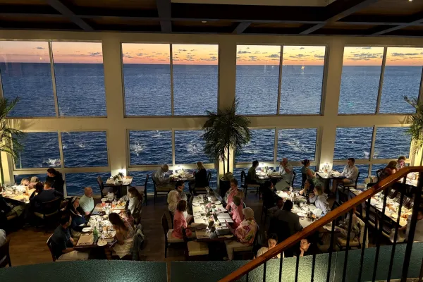 Patrons dining at Ocean Grill in Bermuda, a restaurant with bay windows looking out on the ocean