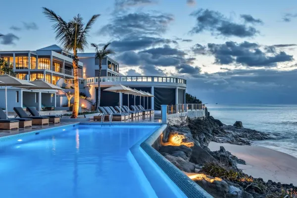 A Bermudian waterfront hotel with a pool at dusk