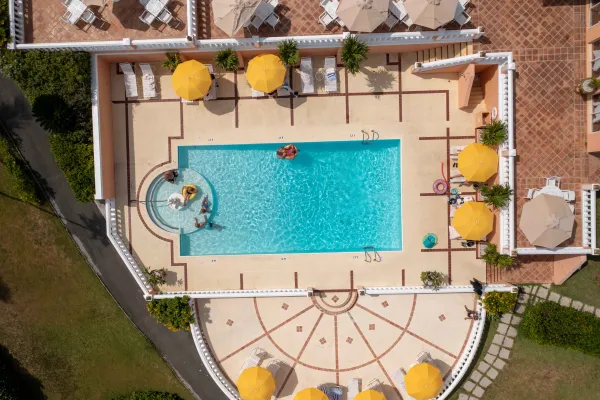An aerial of a pool in Bermuda, surrounded by beach chairs and yellow umbrellas