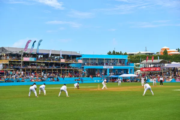 Cricketers on the pitch for Cup Match in Bermuda, as spectators look on