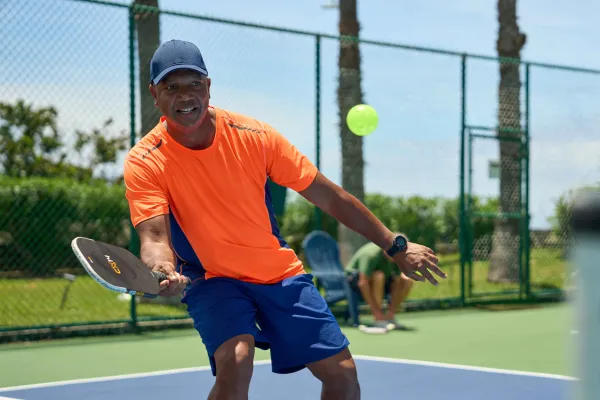 A man returns a pickleball serve on a court in Bermuda