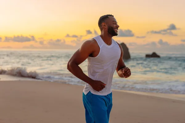 A smiling man running on a Bermuda beach at dawn