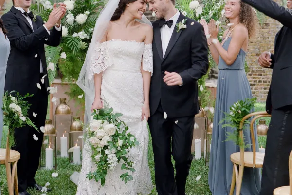 A bride and groom press snuggle and hold hands as they walk down the aisle after getting married at the Unfinished Church in Bermuda