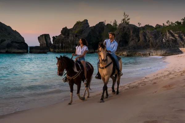 A couple horseback riding on the beach