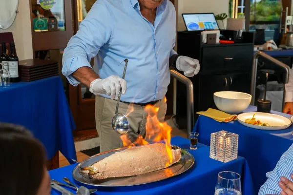 A man is cooking with fire by a table.