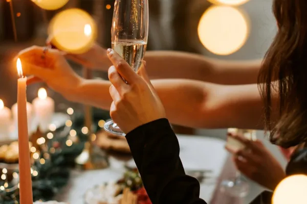 A woman's hand is holding a glass at dinner.