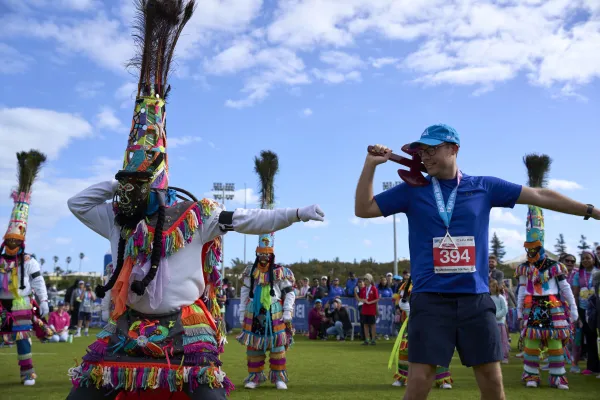 A runner at a Bermuda road race dancing alongside a Gombey dancer