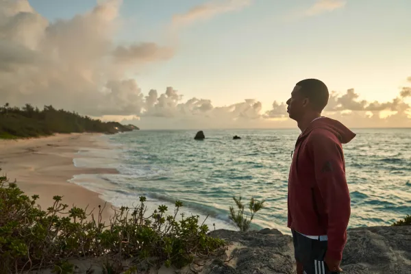 A man looking at the ocean on a Bermuda beach at dusk