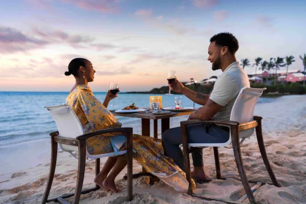 A couple is making a toast on the beach.