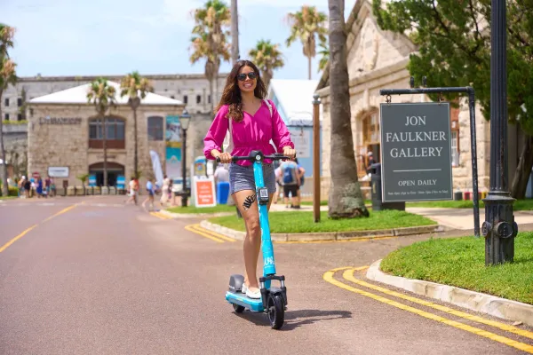 A woman rides a motor scooter down a road in Bermuda