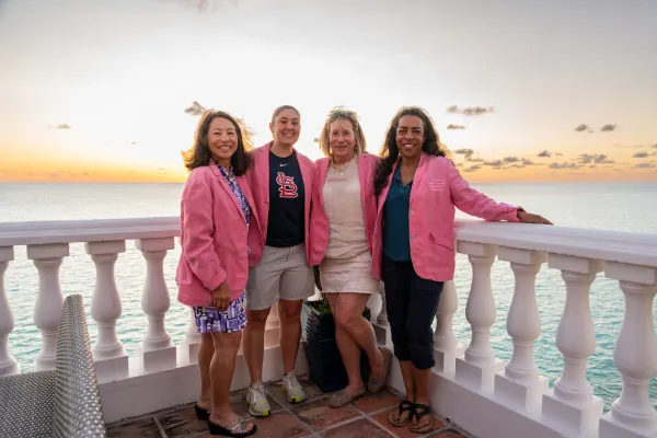 Female golf team in pink blazers on a balcony at sunset, at the Ladies Pro Am tournament in Bermuda