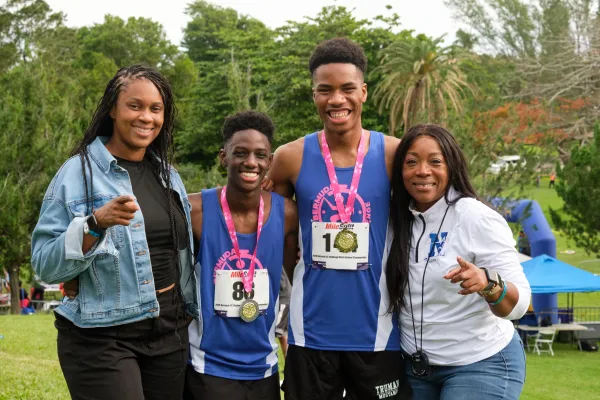 Two track athletes with medals pose with their families in Bermuda
