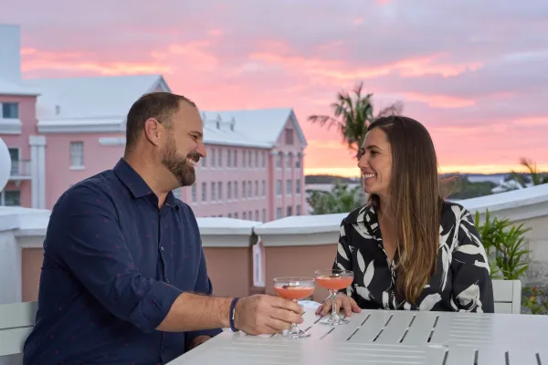A couple enjoying cocktails on a Bermuda balcony