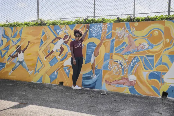 Katura is posing by her name on a mural.