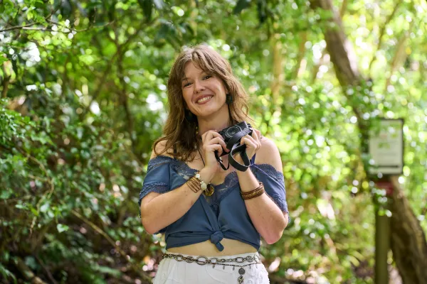 Tristan is holding a camera in the woods