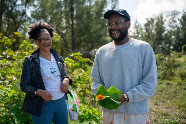 Two people are smiling holding plants
