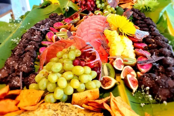 A colourful spread of fruits on a table covered in palm leaves.